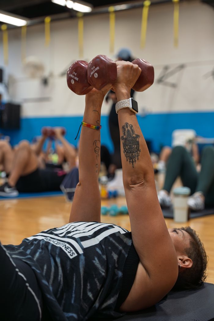 Focused individual lifting dumbbells during a group exercise class in Seattle gym.