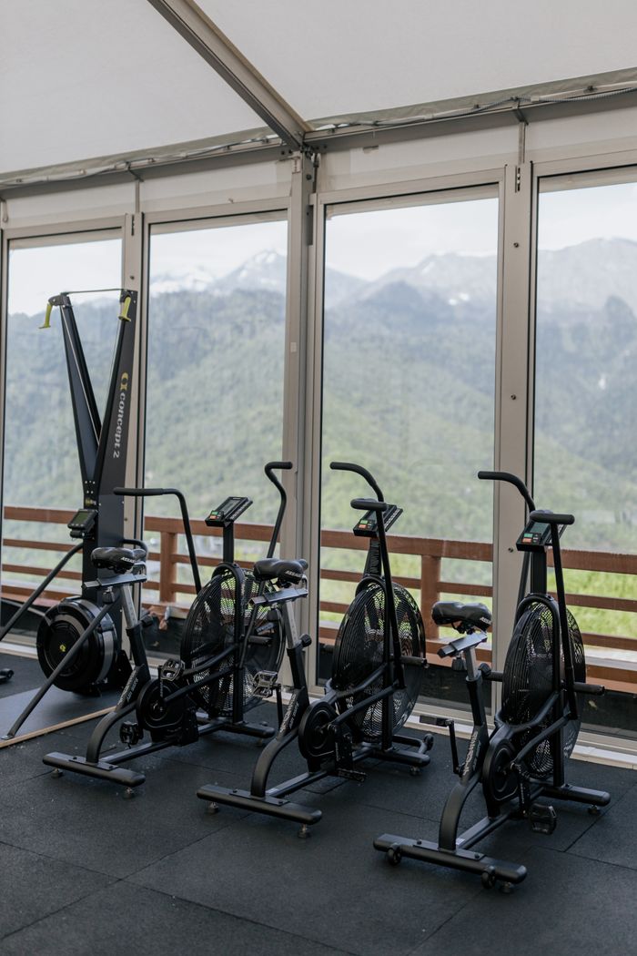 Indoor gym setup with stationary bikes facing scenic mountain views through large windows.